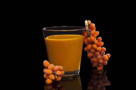 Sea buckthorn juice and berries isolated on black background. Natural detox. Healthy berry eating.