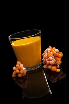 Sea buckthorn juice and berries isolated on black background. Alternative medicine. Healthy fruit eating.