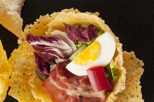 Parmigiano cheese basket filled with bacon and fresh vegetable. Culinary cheese eating. 