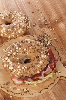 Whole grain bagel with bacon on wooden background. Culinary bagel eating.