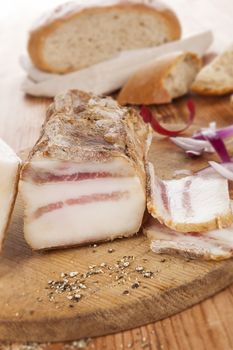 Traditional bacon background with onion and bread on wooden background, rustic style. Delicious meat eating.