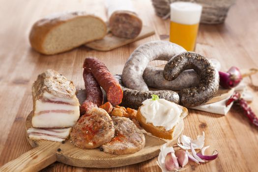 Blood sausage, rice sausage, head cheese, garlic, onion beer and bread on wooden kitchen board on wooden background. Traditional pork meat eating. 
