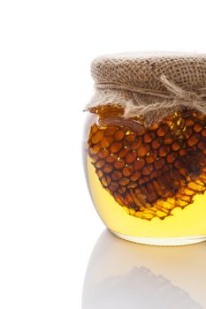 Organic honey with honey comb in glass jar isolated on white. Natural healthy sweetener.