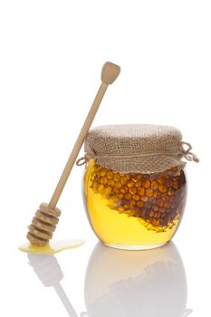 Organic bee honey in glass jar isolated on white background with wooden honey spoon. Healthy alternative medicine.