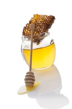 Organic bee honey in glass jar with wooden honey spoon and bee comb. Luxurious bee background.