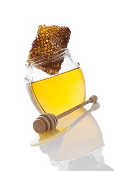 Honey in glass jar with wooden honey spoon and honey comb isolated on white background. Delicious healthy organic bee honey.