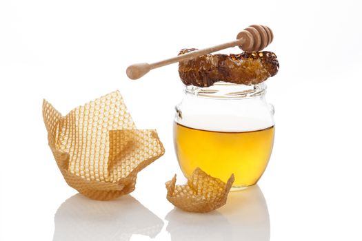 Organic honey with honey comb and wooden dipper isolated on white. Natural healthy sweetener. Alternative medicine.