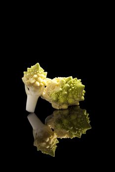 Romanesque cauliflower pieces isolated on black background. Healthy raw food eating. Culinary fresh vegetable.