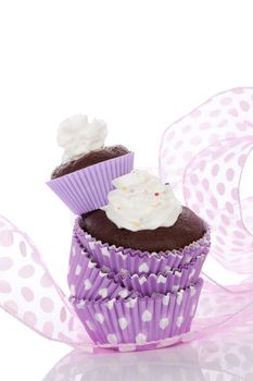 Delicious chocolate cupcake with whipped cream in purple dotted paper form isolated on white. Cupcakes baking.