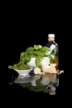 Italian eating. Green basil pesto, fresh green herbs and olive oil isolated on black background. Culinary eating.