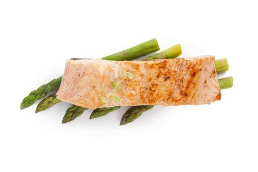Delicious grilled salmon piece with fresh herbs on green asparagus on white background, top view. Healthy fish eating. 