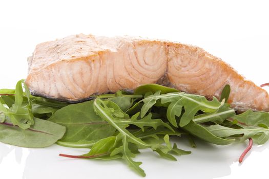 Salmon steak on green salad on white background. Healthy fish eating.
