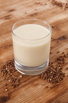 Vegan milk drinking. Buckwheat milk on wooden background. Delicious vegetarian and vegan eating.