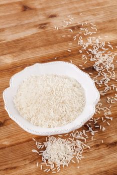 Rice in white vintage bowl on wooden background. Traditional rice eating, rustic style.