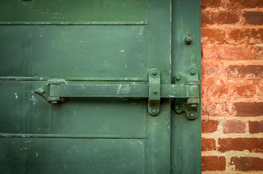 Detail Of Locked Heavy Industrial Green Door With Red Brickwork