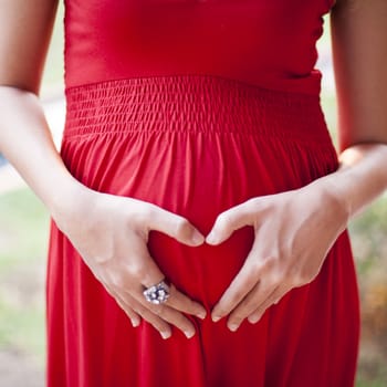 Image of pregnant woman touching her belly with depicting heart on her stomach