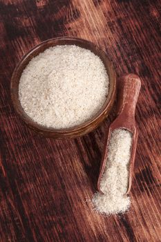 Dietary fiber psyllium in round wooden bowl on dark brown wooden background, top view. Healthy eating concept.