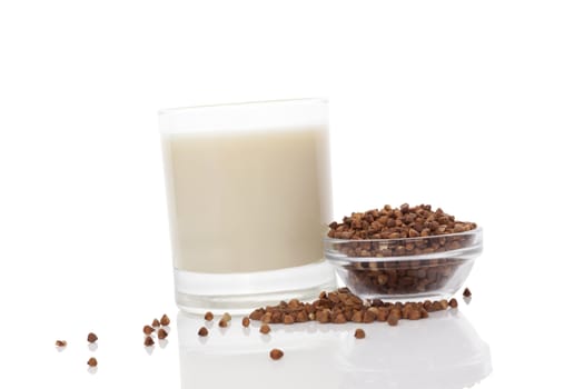 Buckwheat milk in glass with dry buckwheat seeds in glass bowl  isolated on white background. Vegan and vegetarian milk concept.