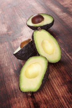 Delicious fresh ripe cut avocados on dark wooden background. Healthy fruit eating.