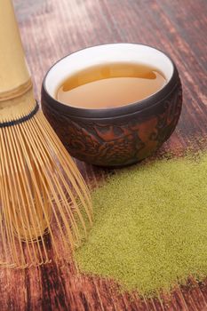 Traditional green powdered tea matcha on wooden background with bamboo chasen and cup of tea. Tea drinking. 