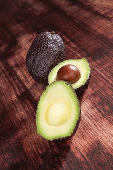 Perfect ripe cut avocados on wooden background. Culinary healthy eating.
