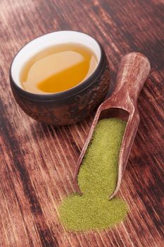 Traditional green powdered tea matcha with cup of tea on wooden background. Japanese oriental tea ceremony.