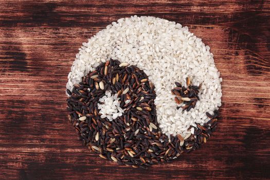 White and wild rice shaped as Yin yang symbol on dark wooden background. Traditional chinese eating and culture.