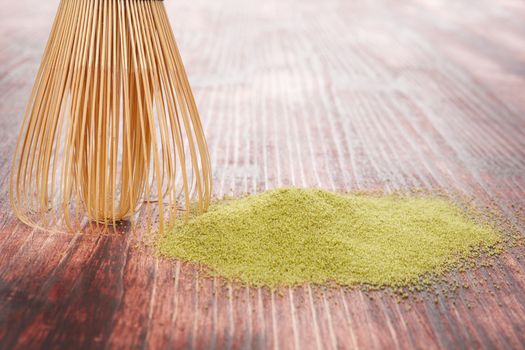Traditional green powdered tea matcha on wooden background with bamboo chasen. Traditional japanese matcha tea ceremony.