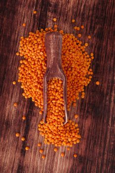 Red lentils on wooden spoon on dark wooden background. Healthy legume eating.