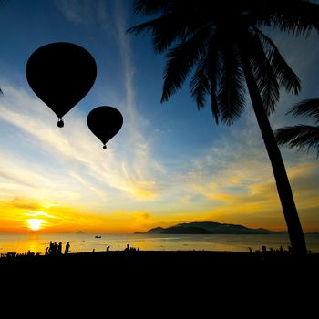 Balloon on Tropical beach with people in silhouette