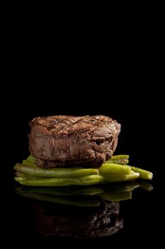 beef steak with beans on black background