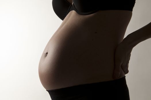 young mother with pregnant belly on background