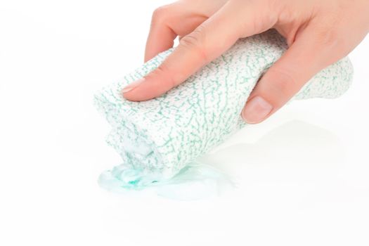 Young female hand holding cleaning sponge dipping into cream soap. Cleaning concept, sparse composition.