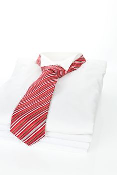 Pile of white business shirts with red striped tie on white background. Contemporary business concept.