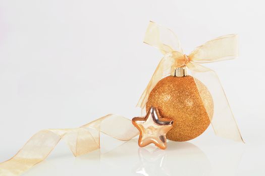 Golden christmas ball and star with ribbon on white background.