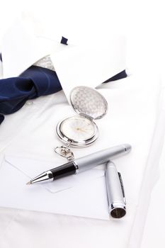 Luxurious business still life with white dress shirt, blue tie, pen, envelope and silver pocket watch. Business concept.