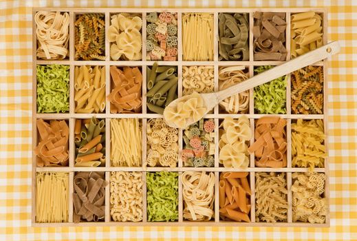Different noodle sorts in wooden box with wooden spoon.