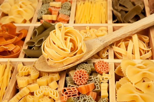 Pasta variation - different pasta sorts in wooden box with wooden spoon.