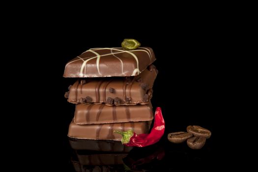 luxurious chocolate with chilli pepper and coffee beans on black background
