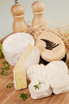 Luxurious cheese variation arranged on wooden board with fresh herbs.