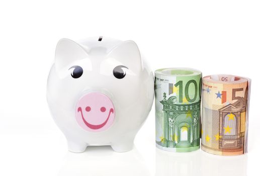 Happy piggy bank with hundred and fifty eur notes bundle next to it isolated on white background. Saving concept.