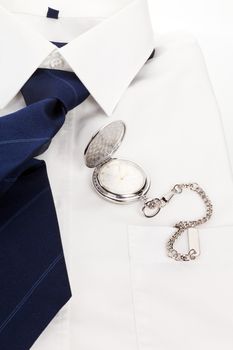 Elegant business still life with white dress shirt, blue tie and luxurious silver pocket watch. Elegance, business and time.