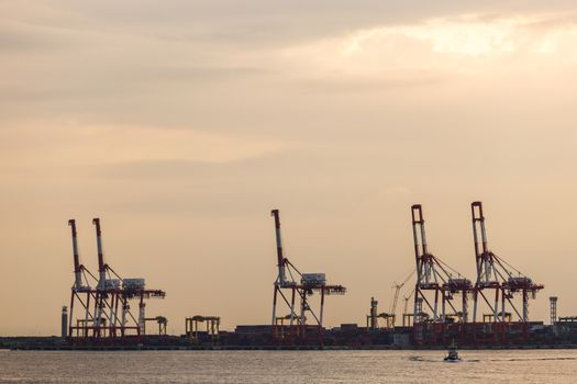 Container stacks and crane in shipyard at sunset for cargo Goods and Logistic background