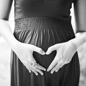 Image of pregnant woman touching her belly with depicting heart on her stomach