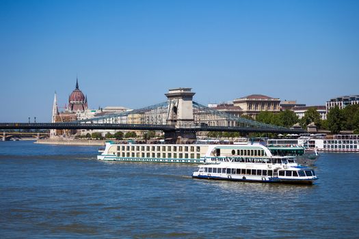 Cruise ships on Danube river with Chain Bridge in front  and Parliament Building in the background, Budapest.