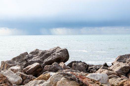 Limestone rocks, pale turquoise ocean and cloud with rain.