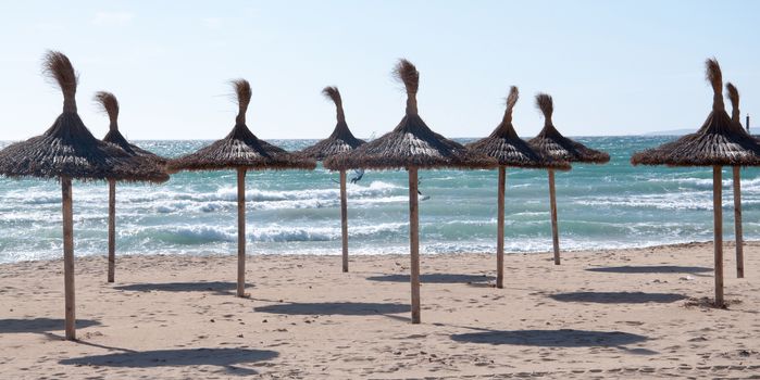 Straw umbrellas on empty beach, Playa de Palma, Majorca, Balearic islands, Spain, in November.