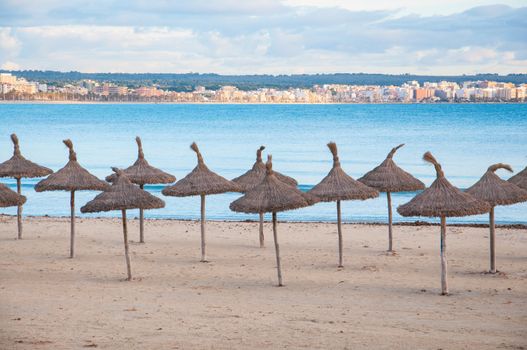 Straw umbrellas on empty beach, Playa de Palma, Majorca, Balearic islands, Spain in February.