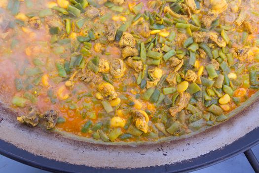 Cooking paella typical from Valencia Spain recipe with rice beans chicken and good hand