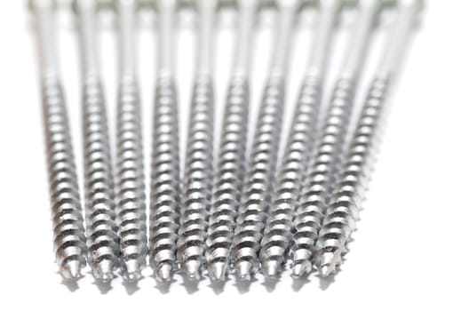 Ten metallic screws on white background; selective focus